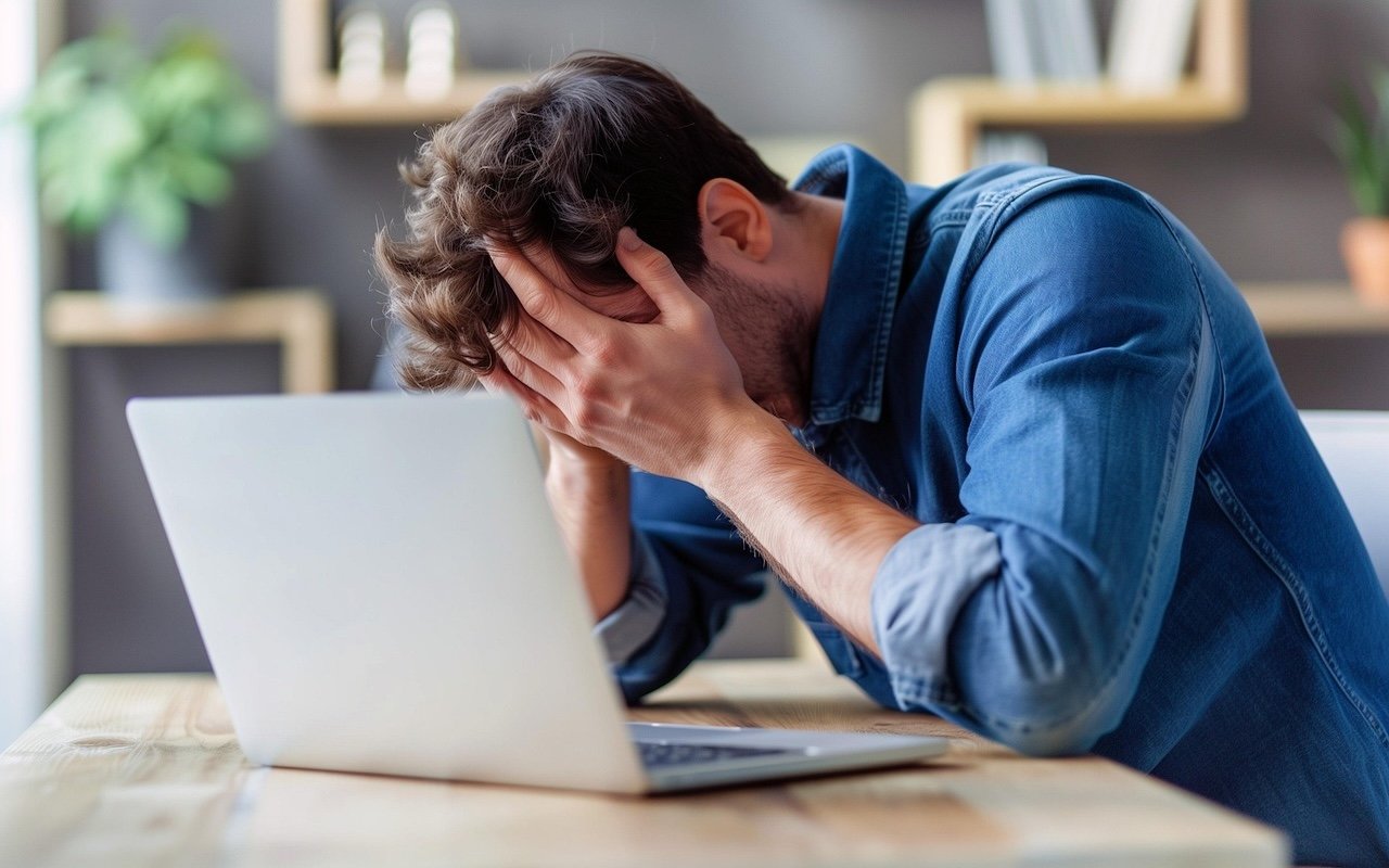 Frustrated college student sitting at desk surrounded by physics textbooks, overwhelmed by homework